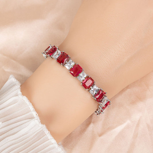 Bracelet with red gemstones on a person's wrist against a neutral background