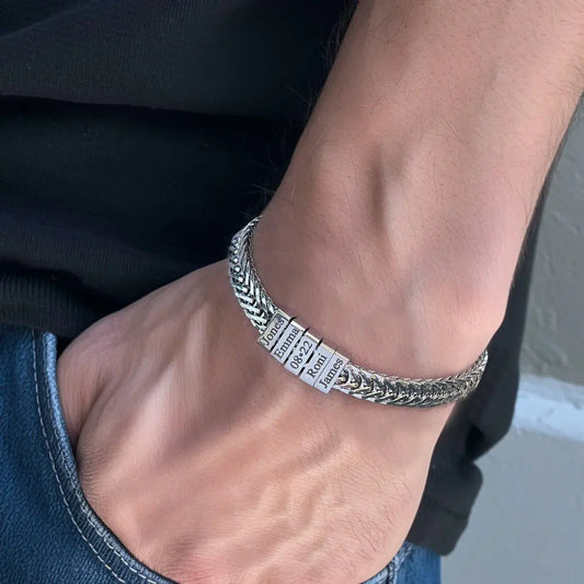 Silver bracelet with engraved text on a wrist against a neutral background