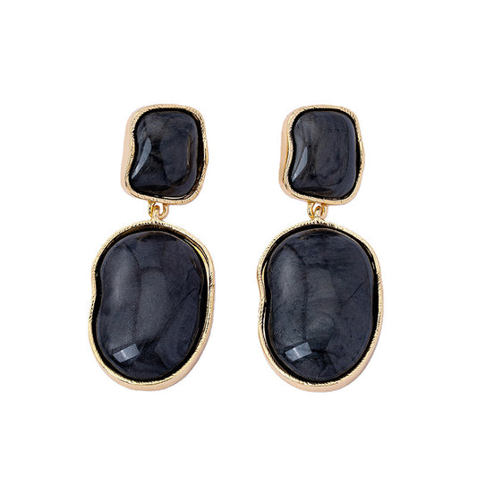 Pair of earrings with black stones and gold accents on a white background