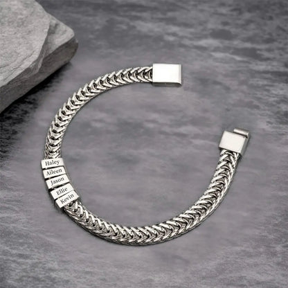 Silver chain bracelet with engraved names on a gray stone surface