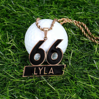 Golf ball with a necklace featuring the number 66 and name 'LYLA' on grass