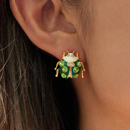 Close-up of a person wearing a green and gold beetle-shaped earring.