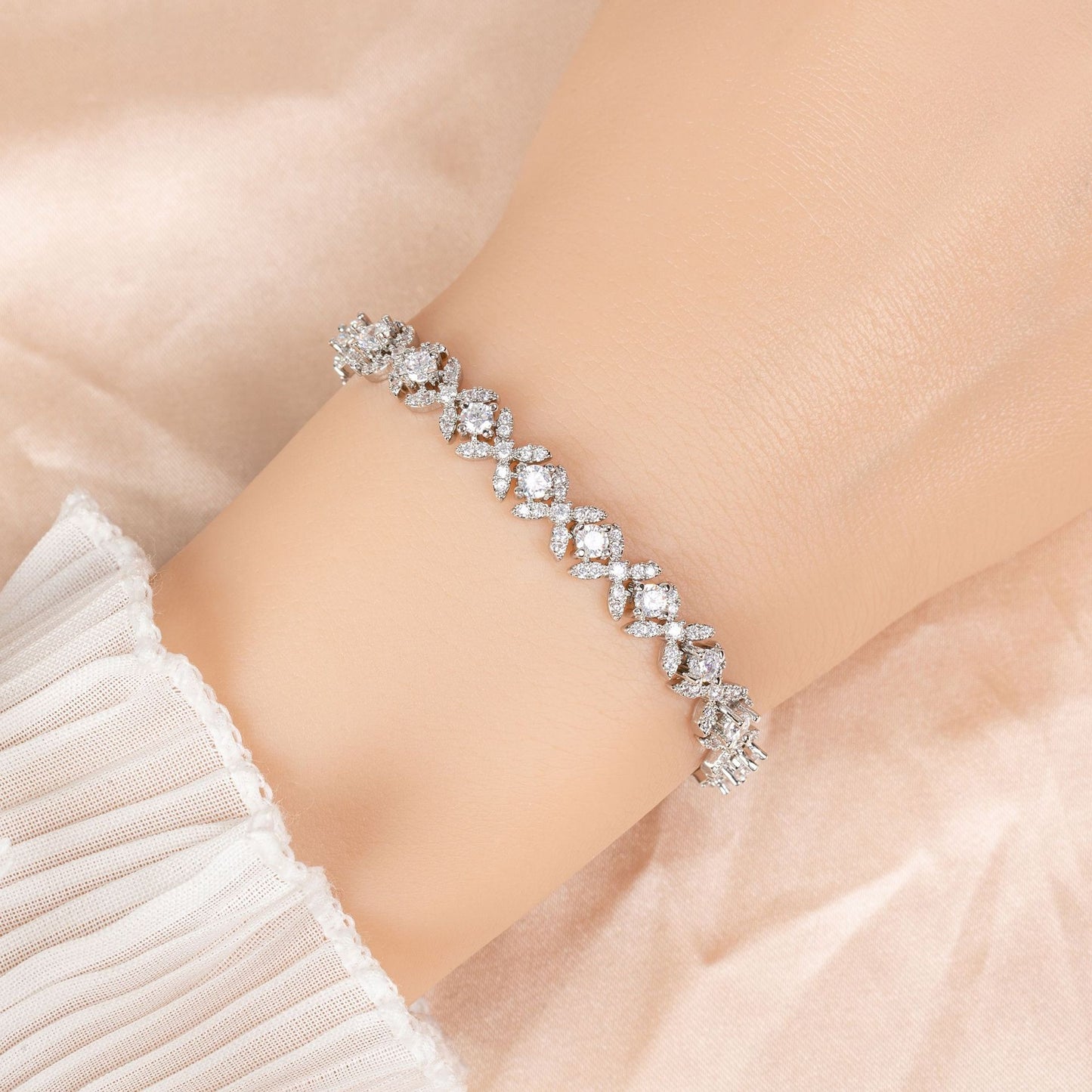 Silver bracelet with clear stones on a wrist against a soft beige background