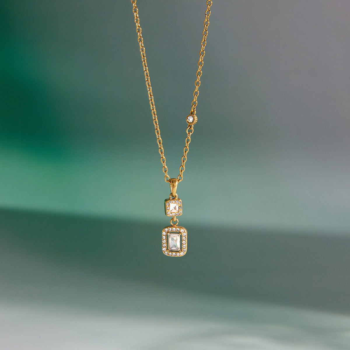 Gold necklace with a pendant on a gradient green background