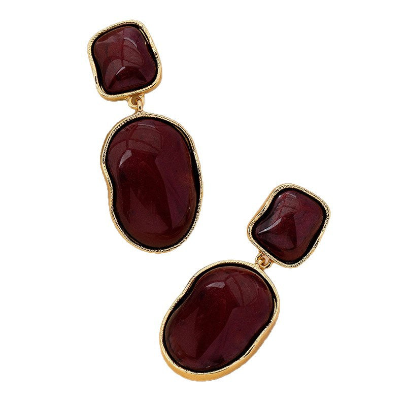 Pair of earrings with gold frames and red stones on a white background