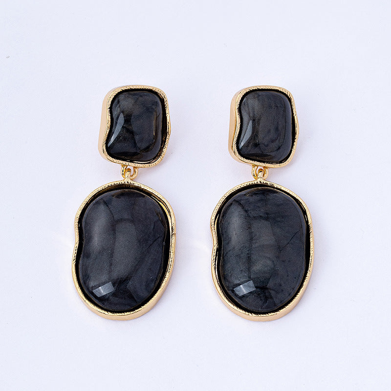 Pair of black stone earrings with gold accents on a white background