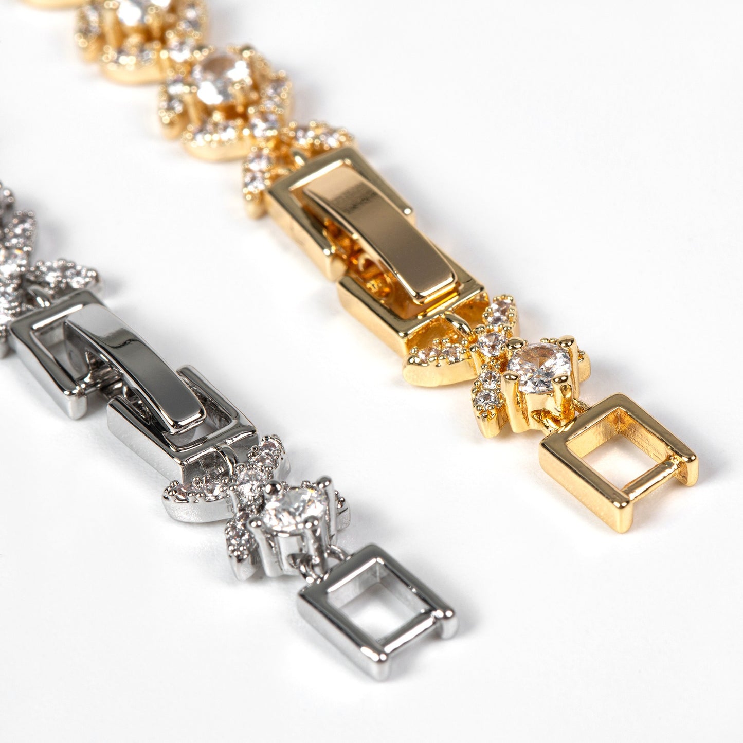 Close-up of gold and silver bracelets with square charms on a white background