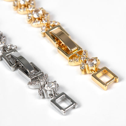 Close-up of gold and silver bracelets with square charms on a white background