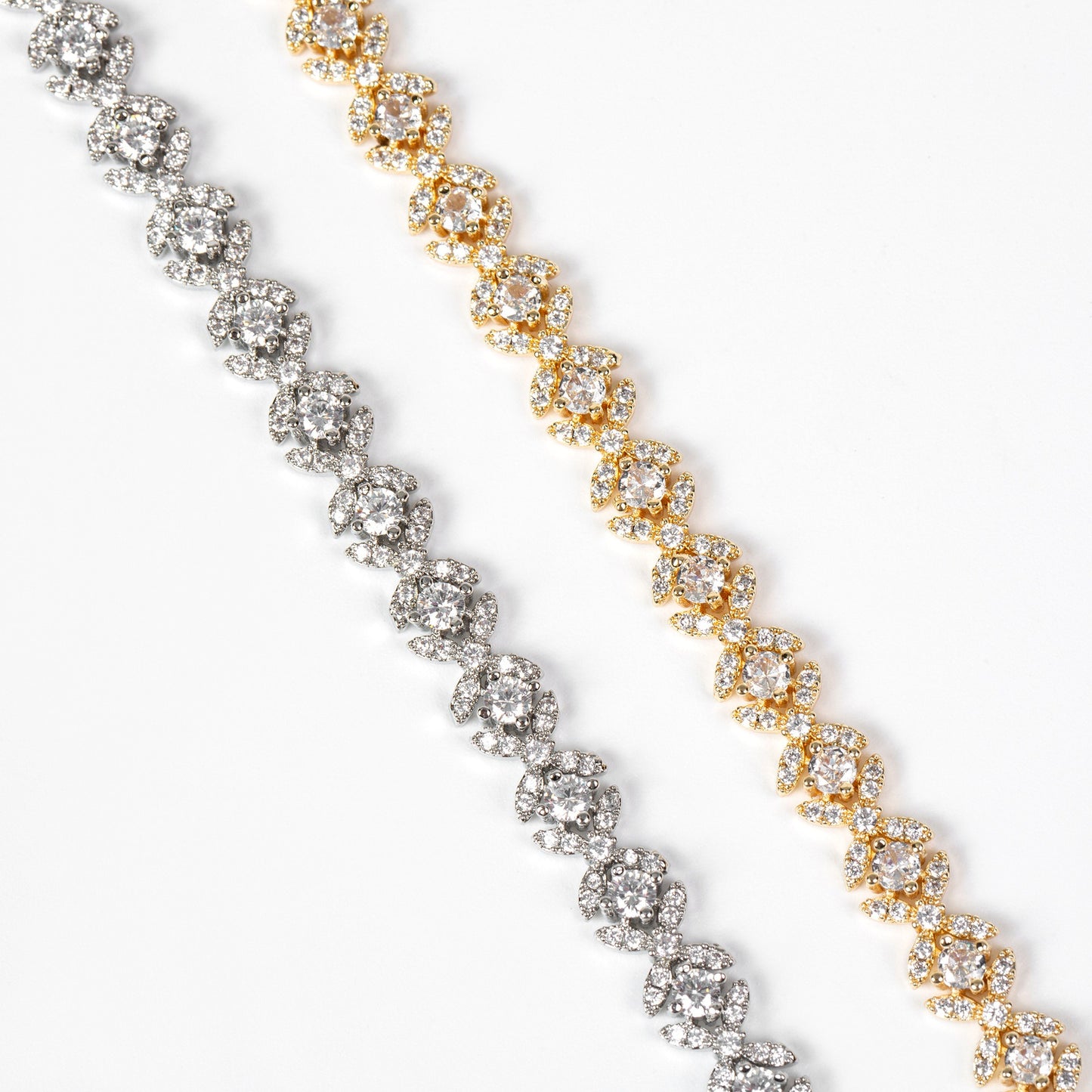 Two diamond tennis bracelets, one gold and one silver, on a white background.
