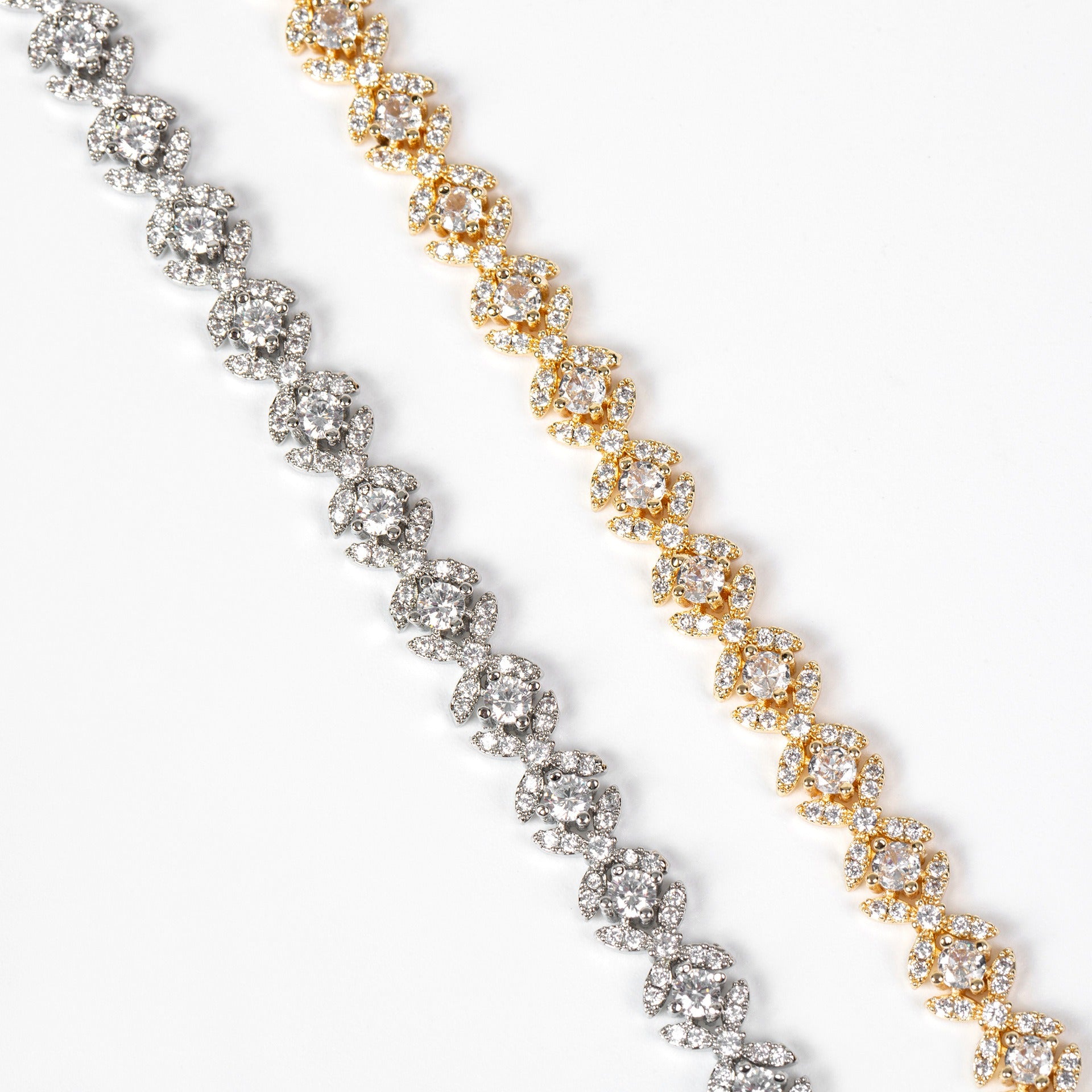 Two diamond tennis bracelets, one gold and one silver, on a white background.