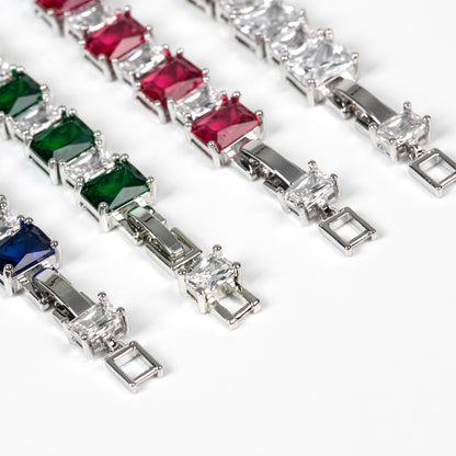 Bracelets with green, red, and blue gemstones on a white background