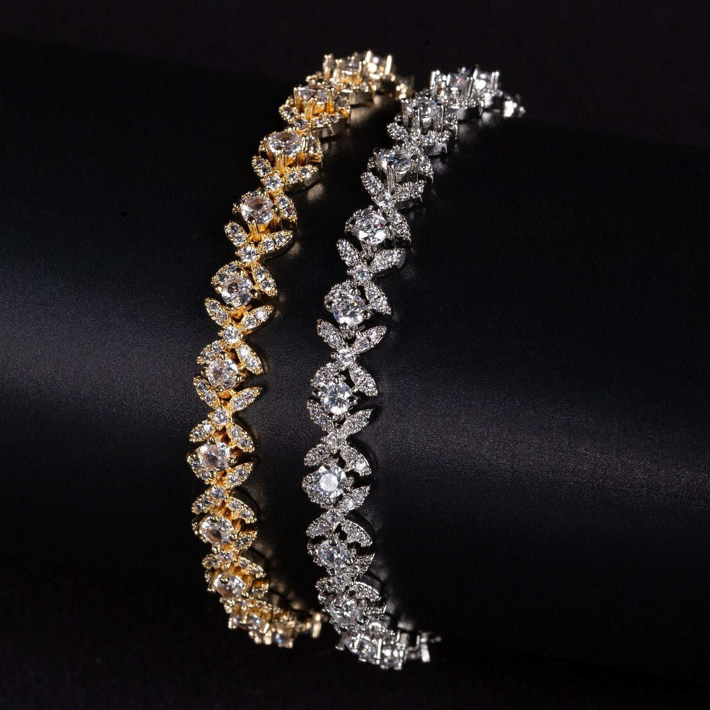 Two diamond bracelets, one gold and one silver, on a black background