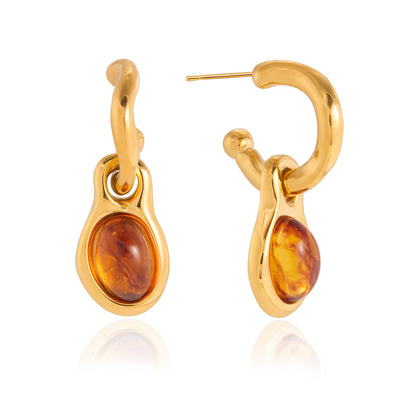 Gold earrings with amber stones on a white background