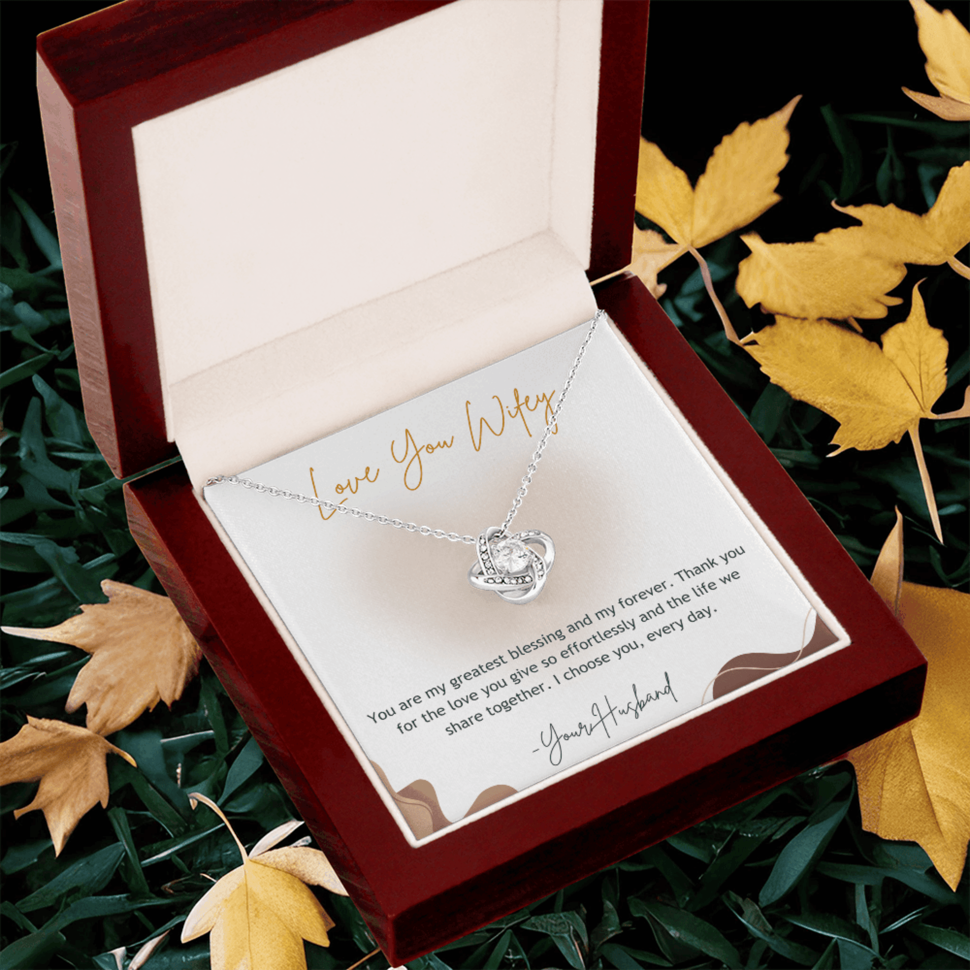 Necklace with heart pendant in a gift box surrounded by autumn leaves