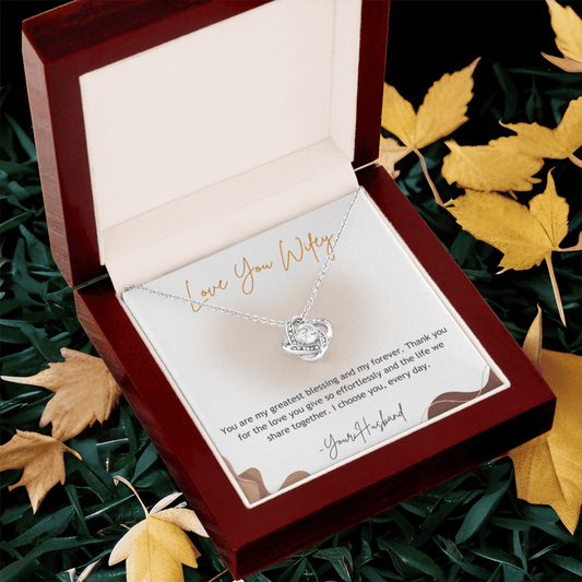 Necklace with heart pendant in a gift box surrounded by autumn leaves