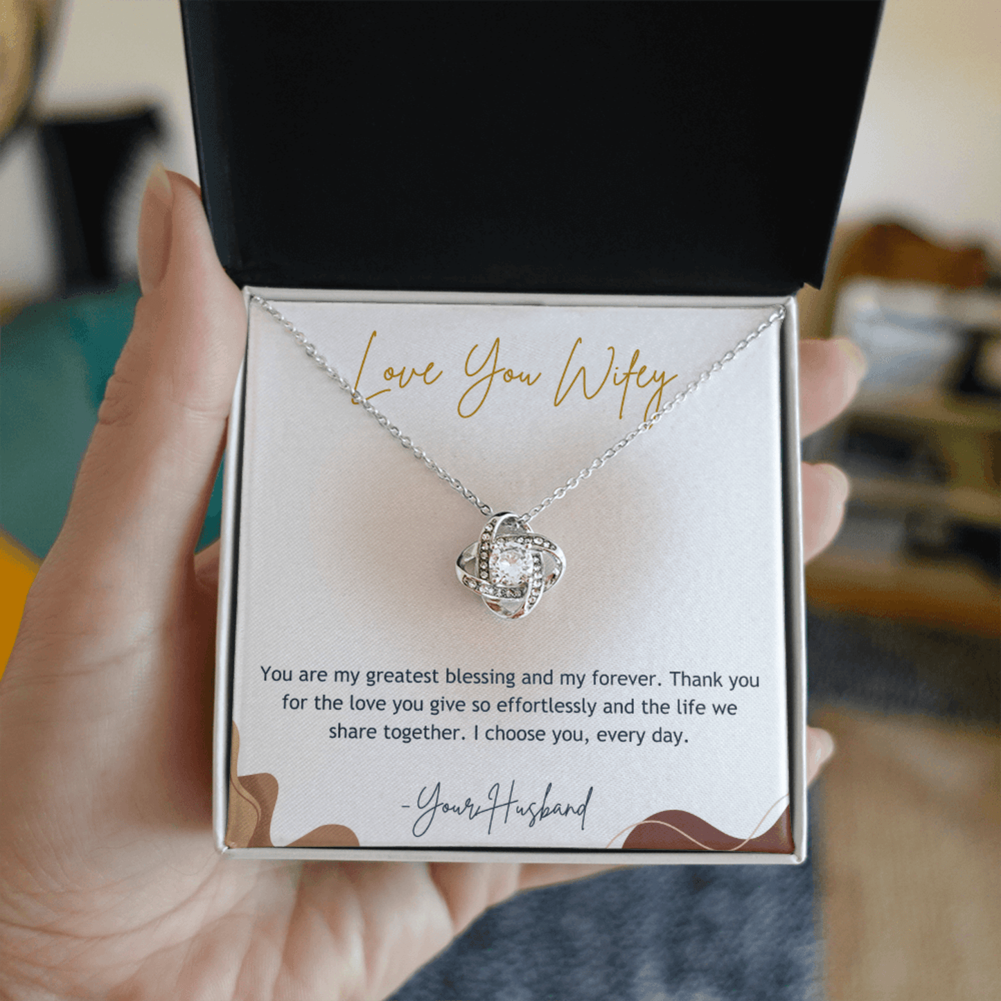 Necklace in a gift box with a sentimental message, held by a hand.
