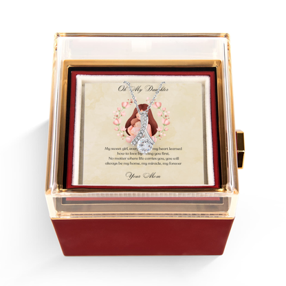 Rotating rose box with a card inside featuring an illustration of a hand holding a baby and text with Alluring beauty necklace.