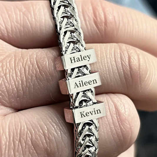 Silver bracelet with engraved names held in a hand