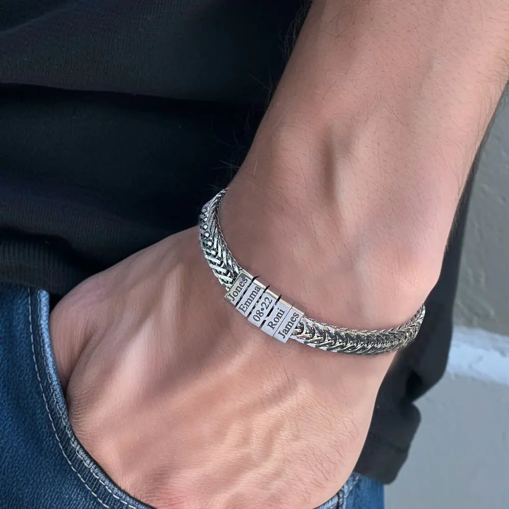 Silver bracelet with engraved text on a wrist against a neutral background