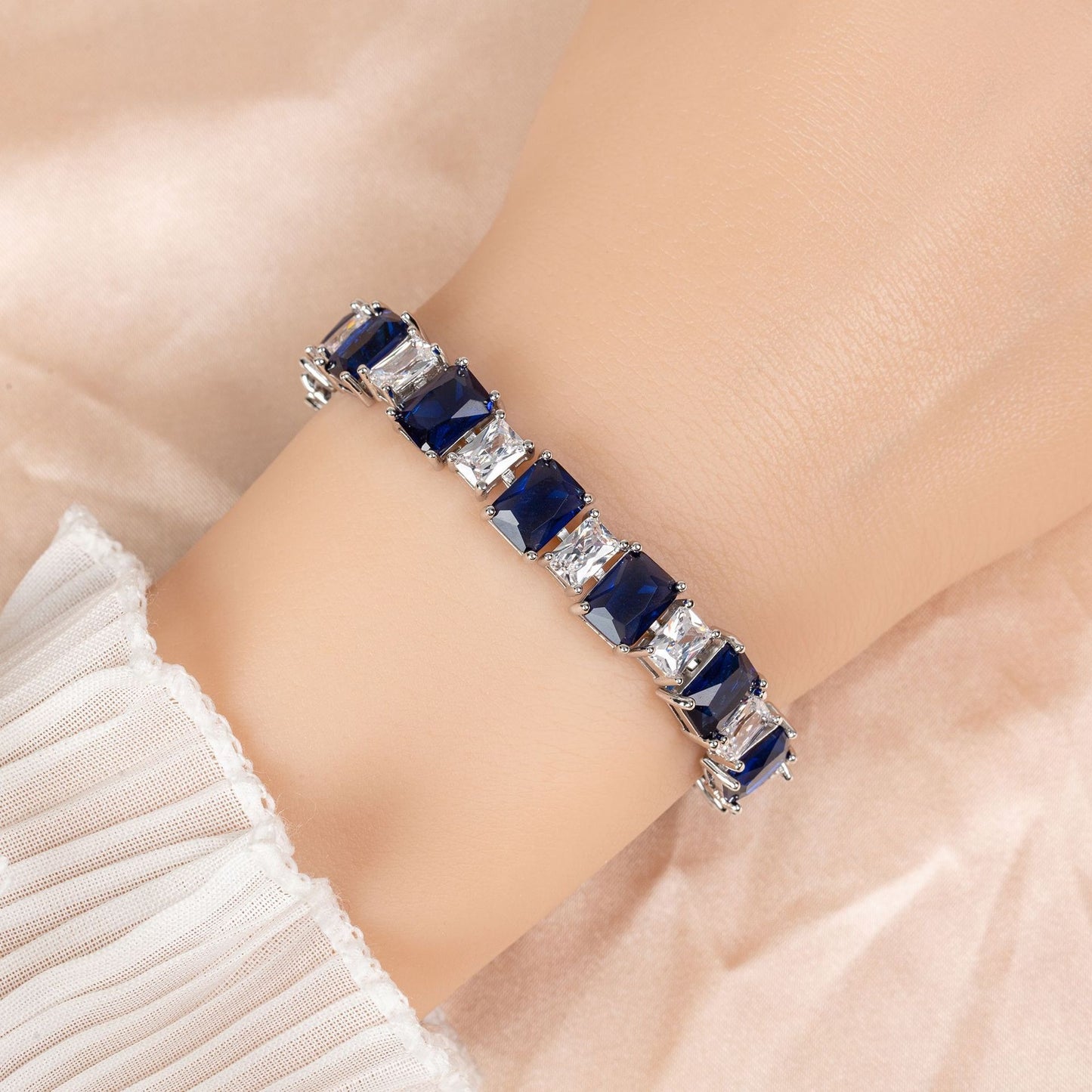 Bracelet with blue gemstones on a person's wrist against a neutral background