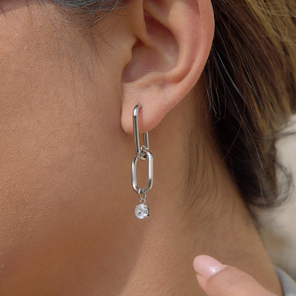 Silver earring with a small gemstone hanging from an ear
