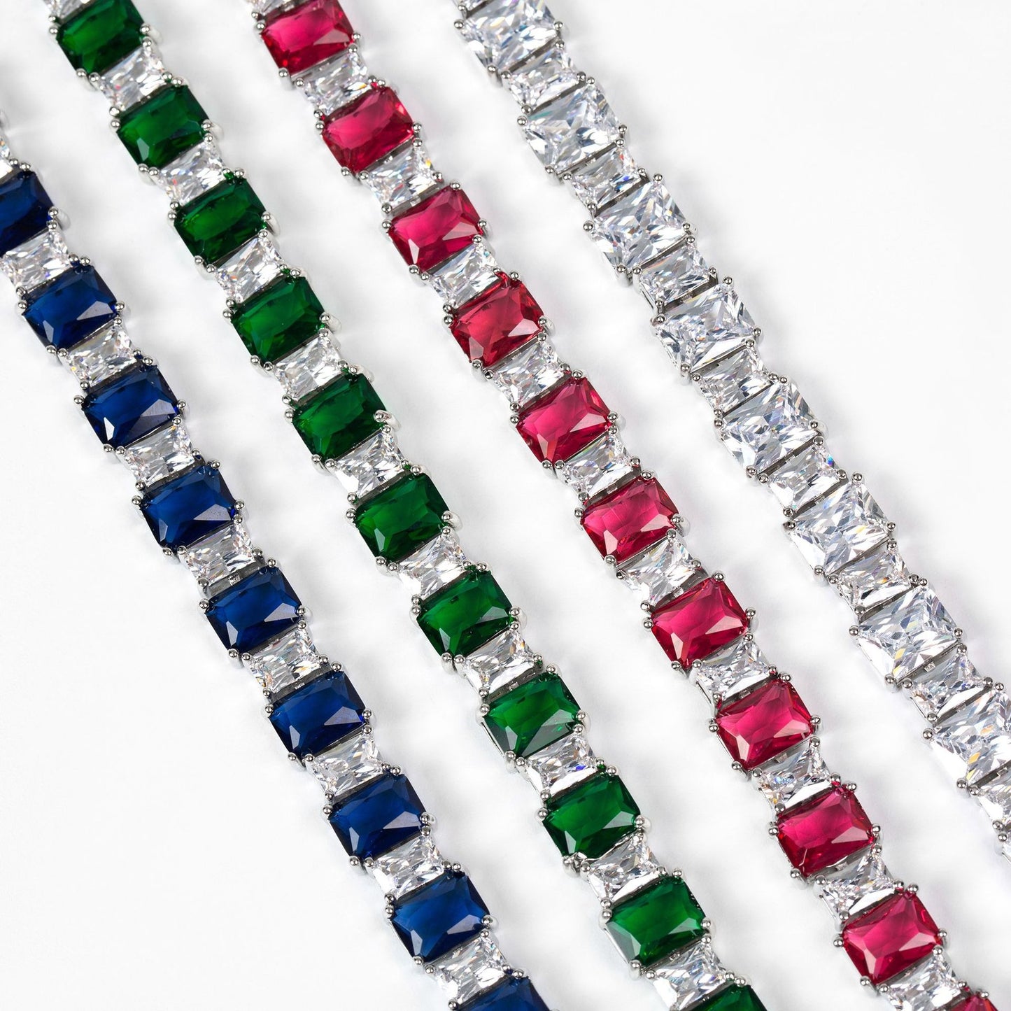 Three diamond bracelets with colored gemstones on a white background
