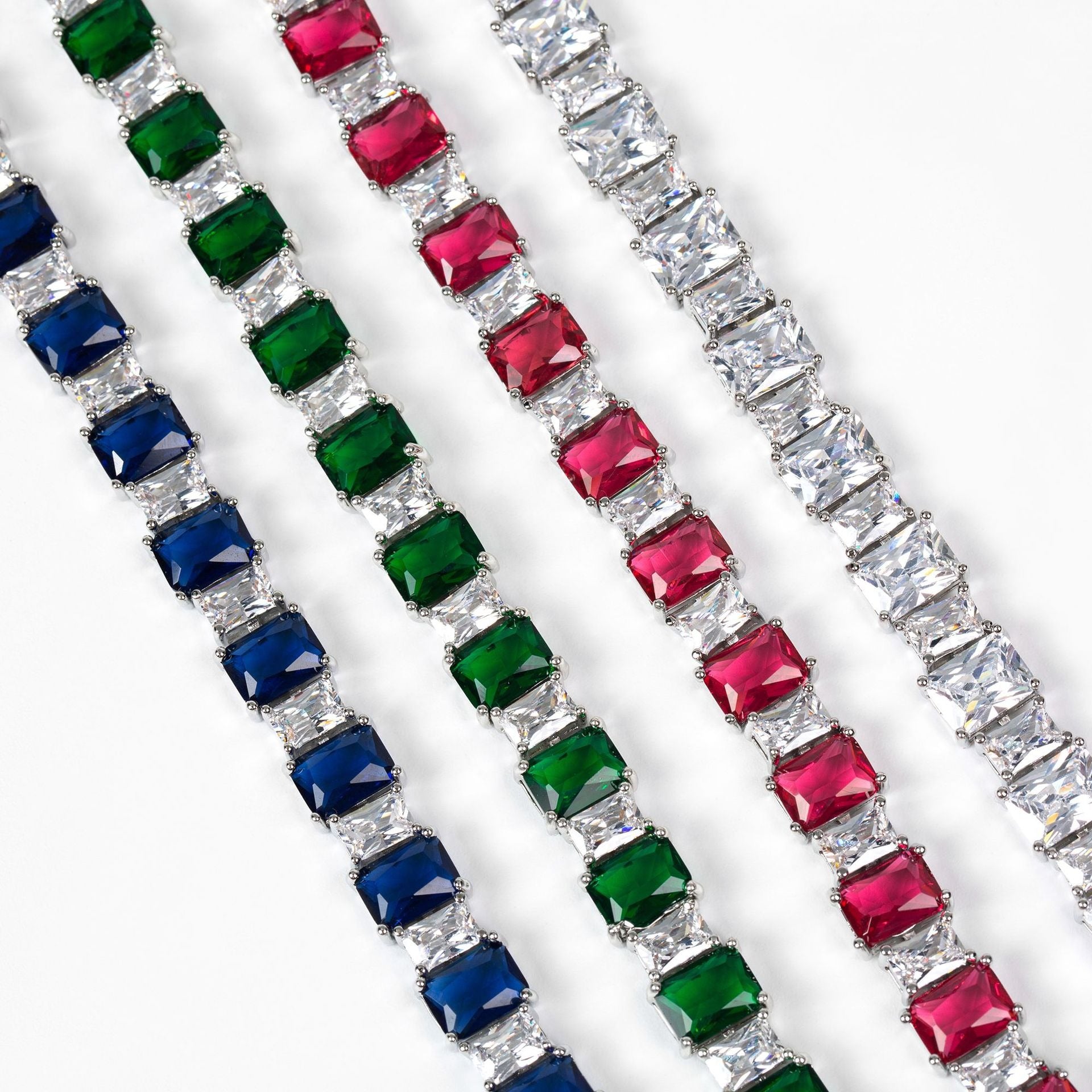 Three diamond bracelets with colored gemstones on a white background