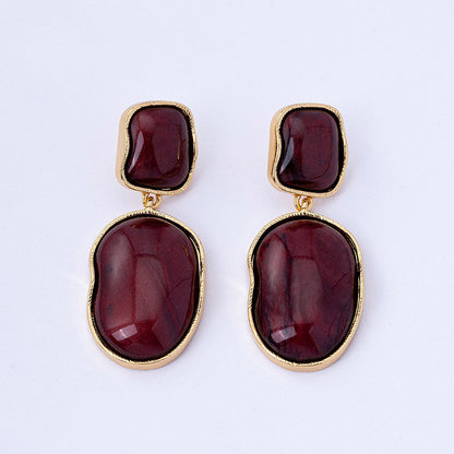 Pair of earrings with gold frames and red stones on a white background