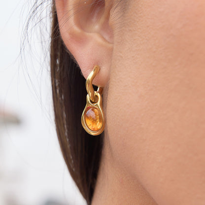 Gold earring with a central gemstone worn by a person