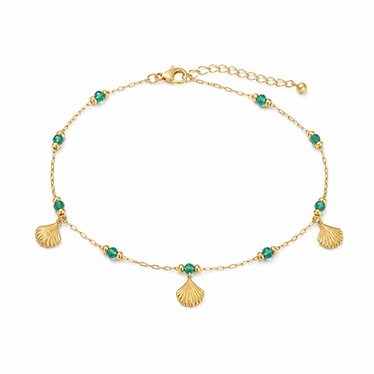 Gold bracelet with green beads and shell charms on a white background