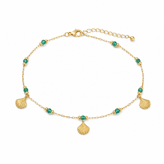 Gold bracelet with green beads and shell charms on a white background